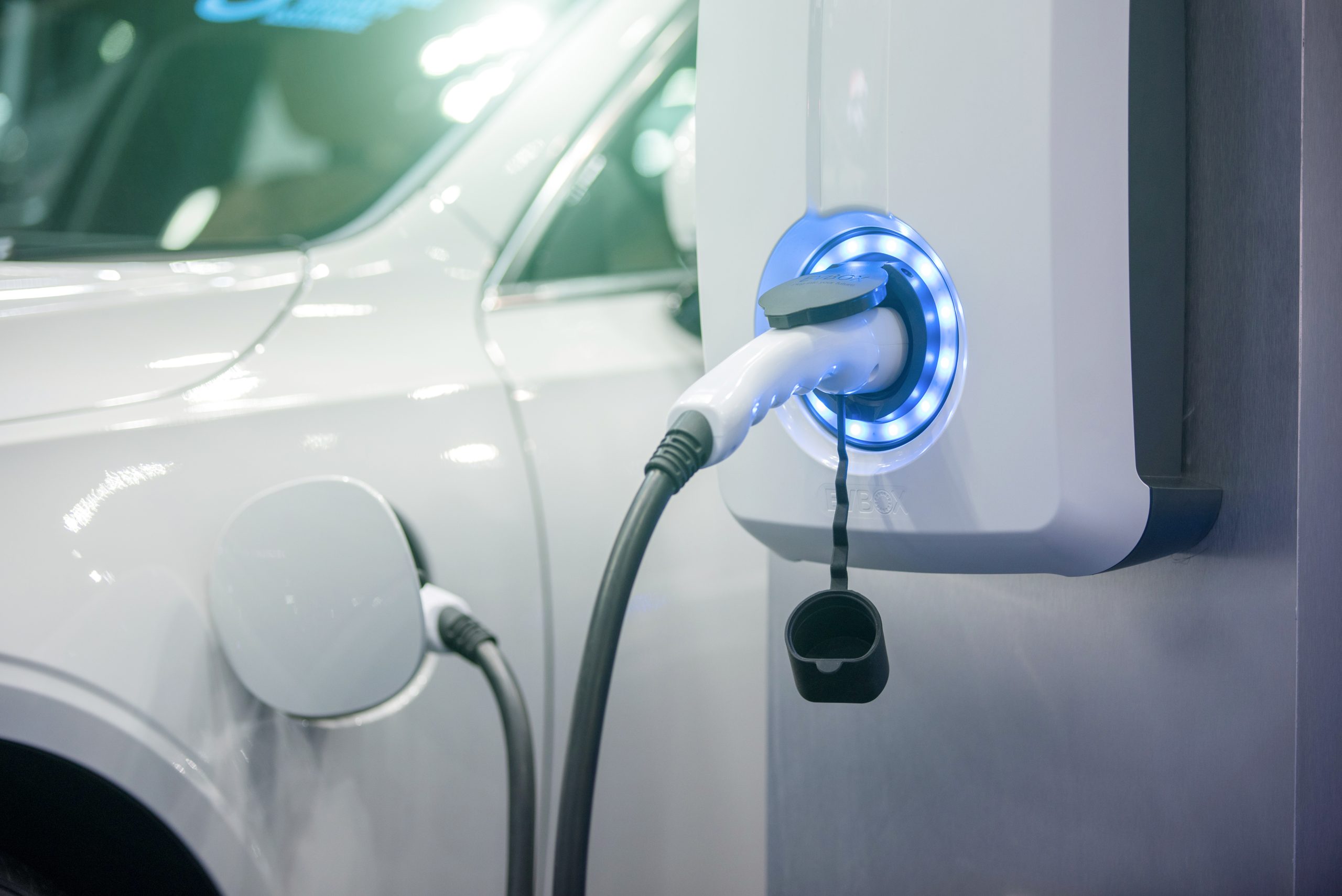 Electric vehicle charging cable plugged into a car at a wall-mounted EV charger